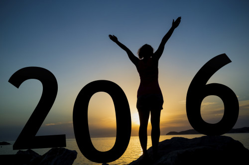 Happy new 2016 year card. A girl standing on a beach, watching the sunset, standing as a part of 2016 sign